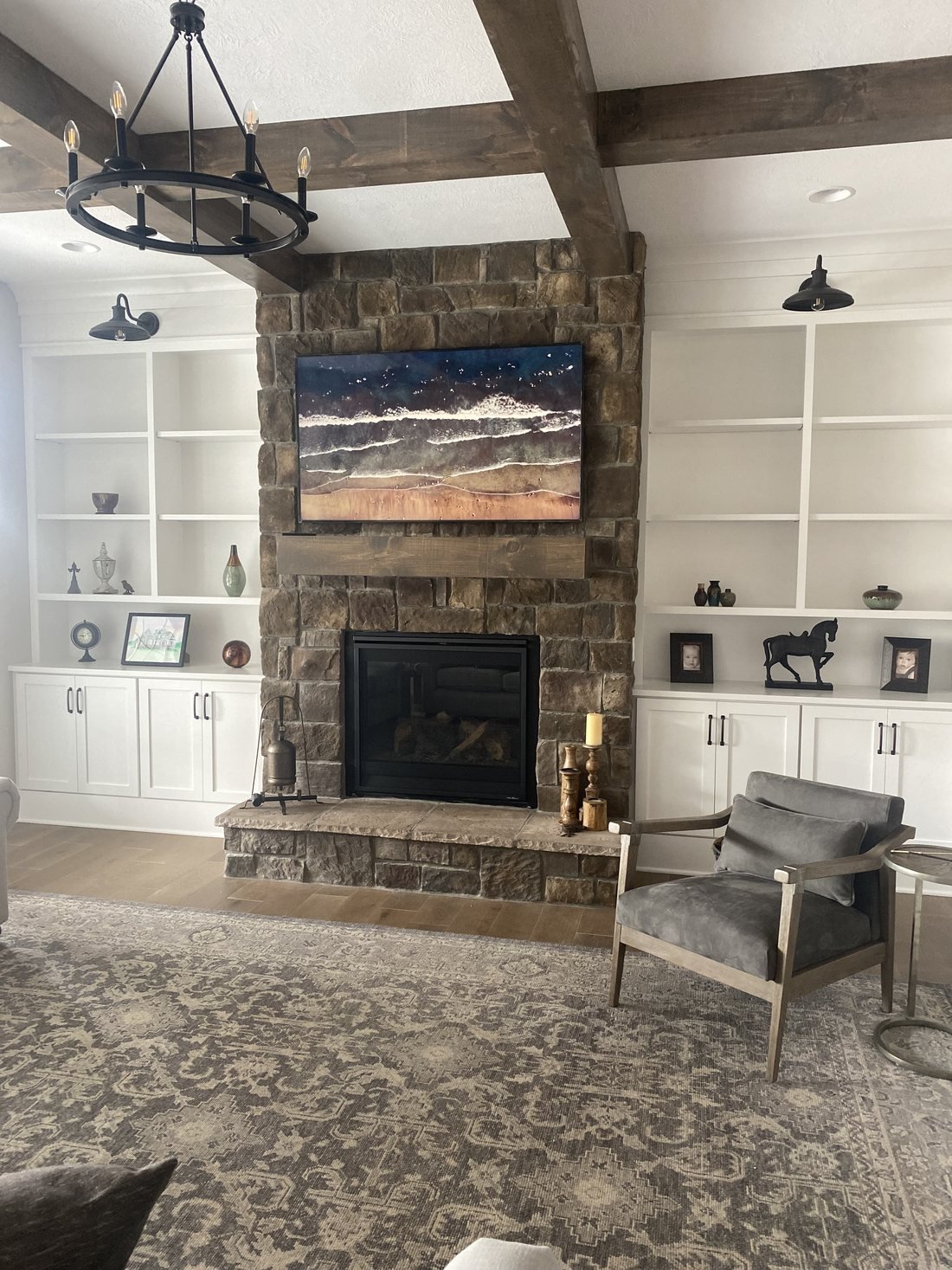 White custom built-in cabinets and shelving on both sides of a stone fireplace