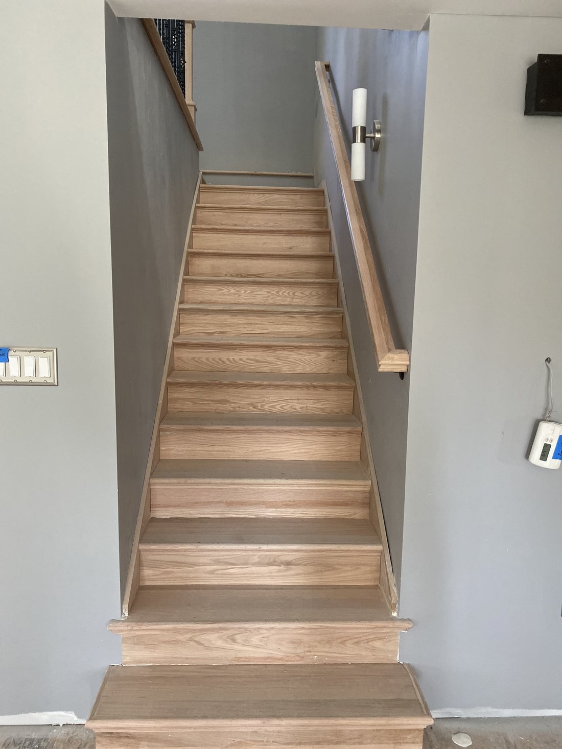 Straight run of custom oak stairs with a wall-mounted oak handrail